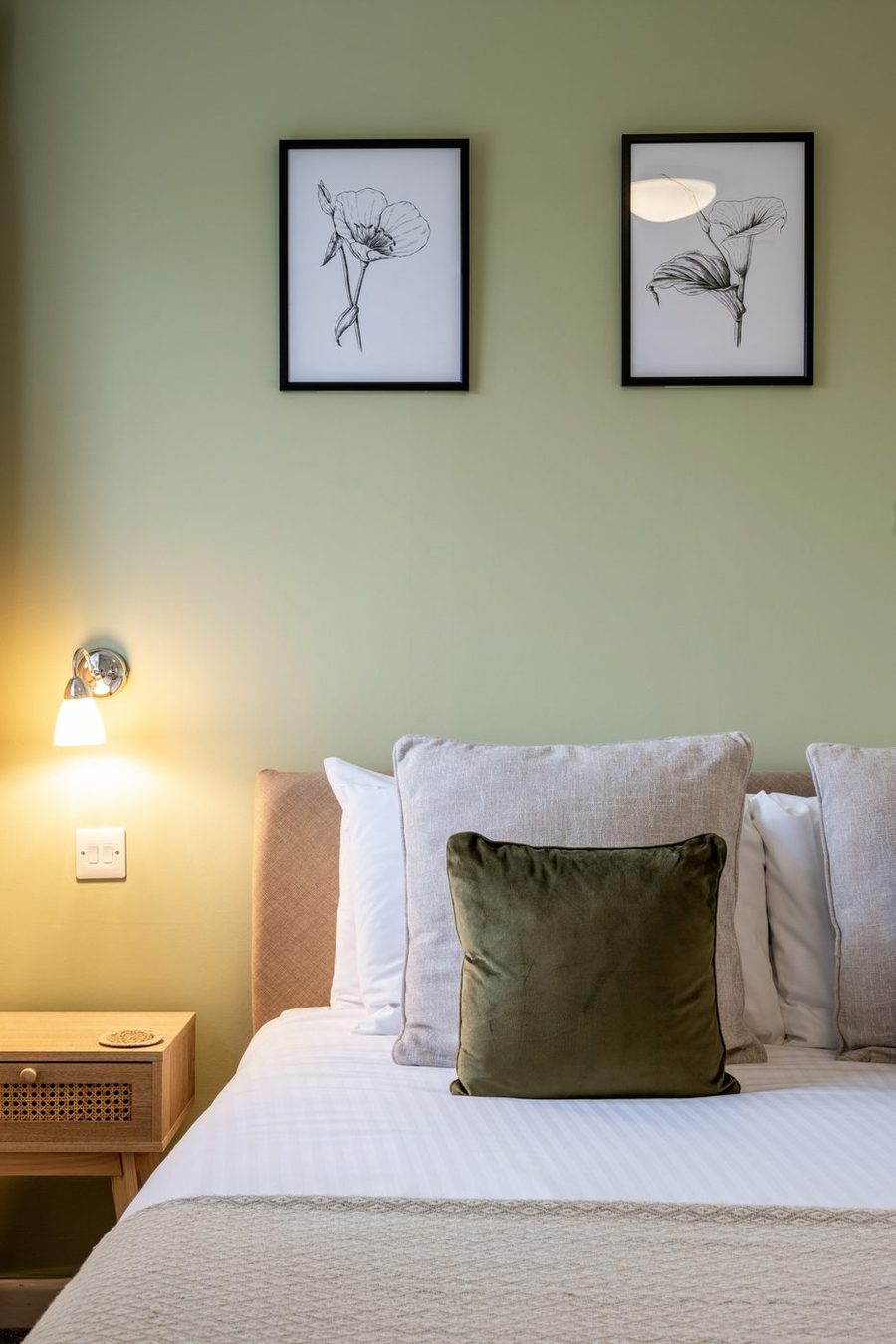 Inn for All Seasons guest room with sage green walls, upholstered headboard and botanical prints